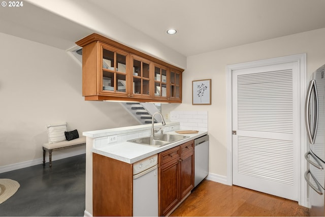 kitchen with a sink, baseboards, light countertops, appliances with stainless steel finishes, and brown cabinets