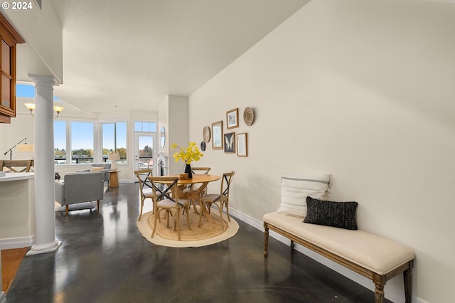 dining room featuring concrete flooring, baseboards, and ornate columns