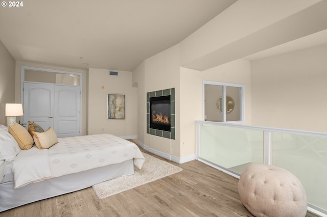 bedroom featuring baseboards, visible vents, a tiled fireplace, and wood finished floors