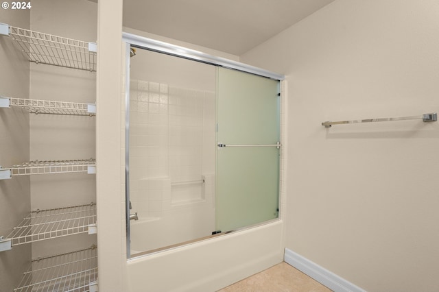 bathroom with shower / bath combination with glass door, tile patterned flooring, and baseboards