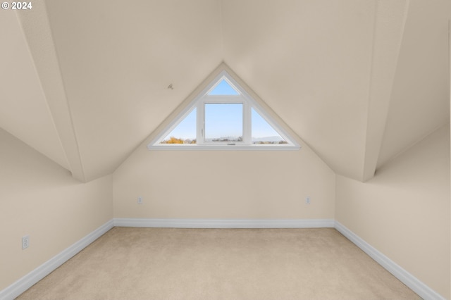 bonus room with baseboards, vaulted ceiling, and light colored carpet