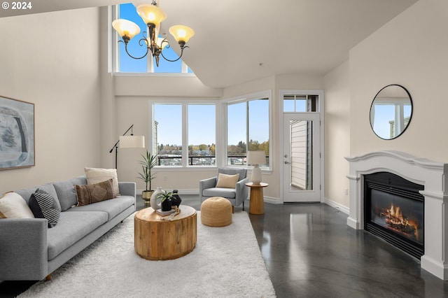 living room with high vaulted ceiling, baseboards, a chandelier, and a glass covered fireplace