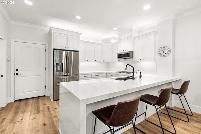 kitchen with stainless steel appliances, kitchen peninsula, a breakfast bar area, and white cabinets