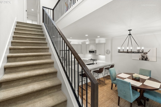 stairway with a high ceiling, wood-type flooring, and a chandelier