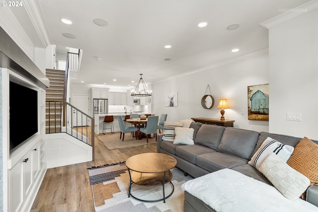 living room with ornamental molding, light hardwood / wood-style floors, and a notable chandelier