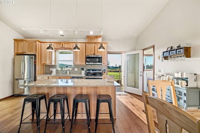 kitchen featuring light hardwood / wood-style floors, a kitchen island, hanging light fixtures, and appliances with stainless steel finishes