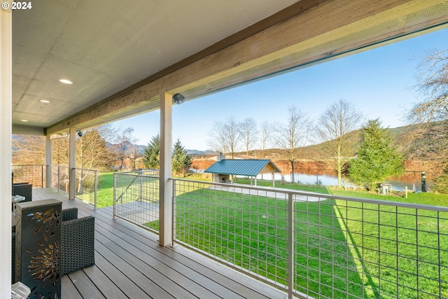 wooden terrace featuring a water view and a lawn