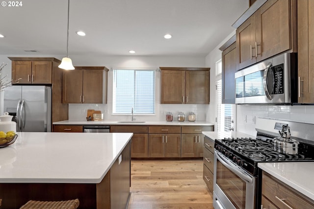 kitchen featuring hanging light fixtures, tasteful backsplash, appliances with stainless steel finishes, and light hardwood / wood-style floors