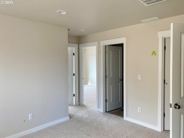 unfurnished bedroom with visible vents, a textured ceiling, baseboards, and carpet flooring