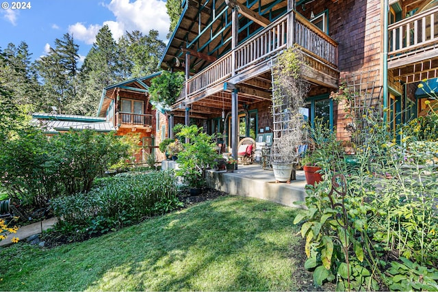 exterior space featuring a patio, a balcony, and a lawn