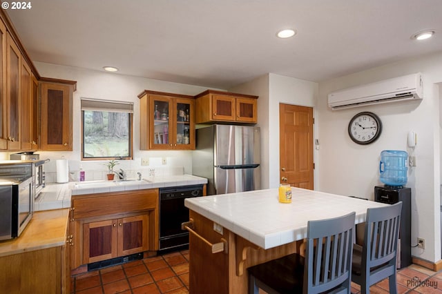 kitchen with sink, a wall mounted AC, stainless steel refrigerator, tile counters, and dishwasher