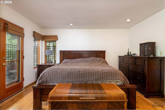 bedroom featuring light hardwood / wood-style floors, multiple windows, and a textured ceiling