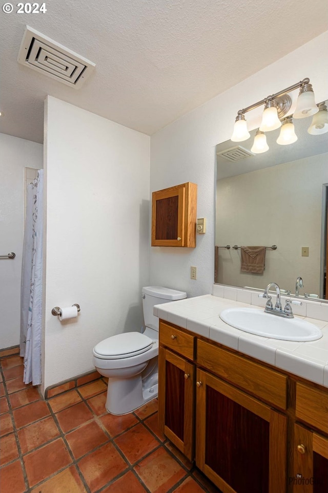 bathroom featuring tile patterned floors, vanity, toilet, and a textured ceiling