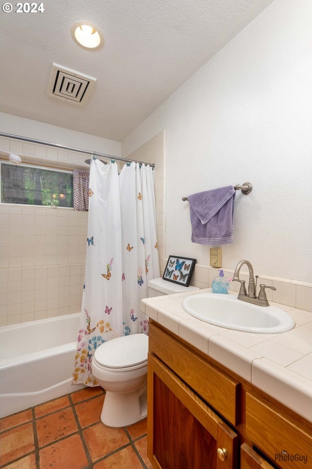 full bathroom featuring toilet, a textured ceiling, vanity, shower / bathtub combination with curtain, and tile patterned flooring