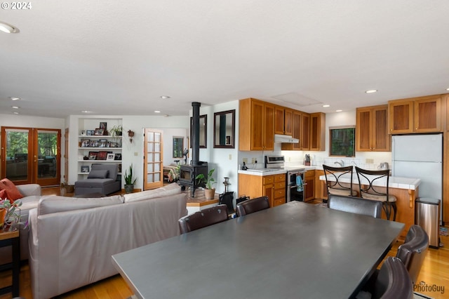 dining room featuring a wood stove, light wood-type flooring, and french doors