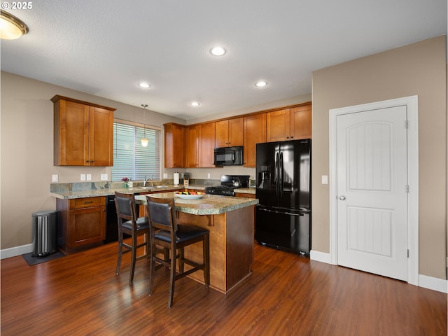 kitchen with light stone countertops, sink, a kitchen bar, and black appliances