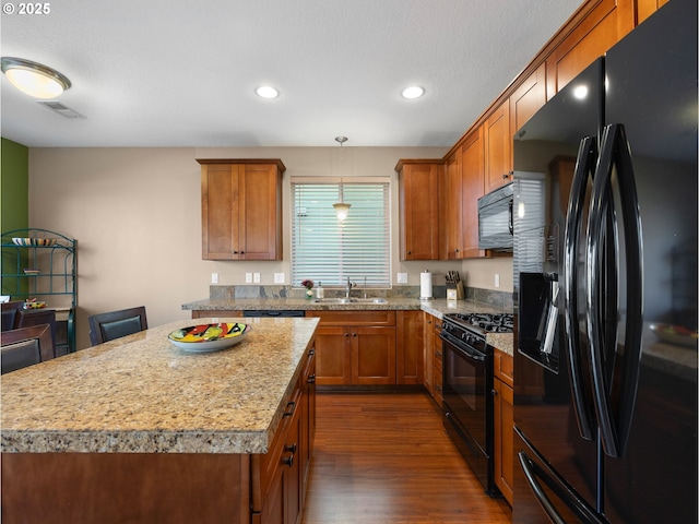 kitchen with a kitchen island, decorative light fixtures, sink, dark hardwood / wood-style flooring, and black appliances