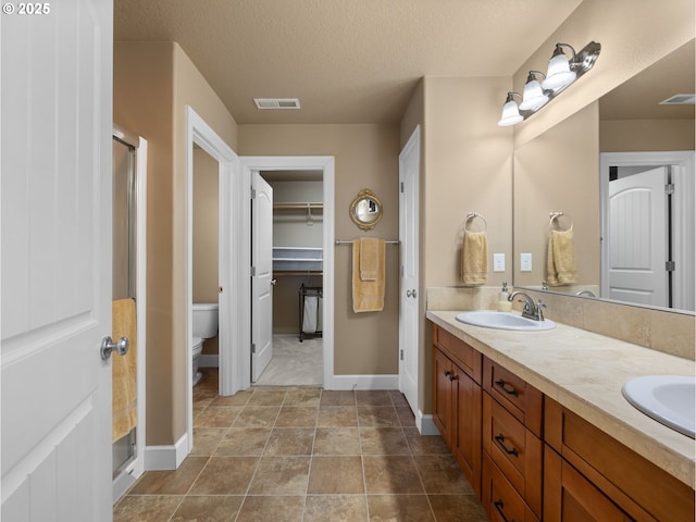 bathroom with tile patterned flooring, vanity, an enclosed shower, toilet, and a textured ceiling