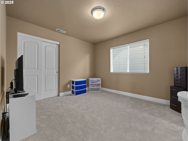 misc room with light colored carpet and a textured ceiling