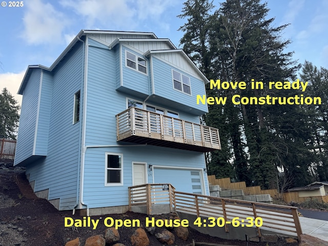 back of property featuring board and batten siding, fence, a balcony, and a garage