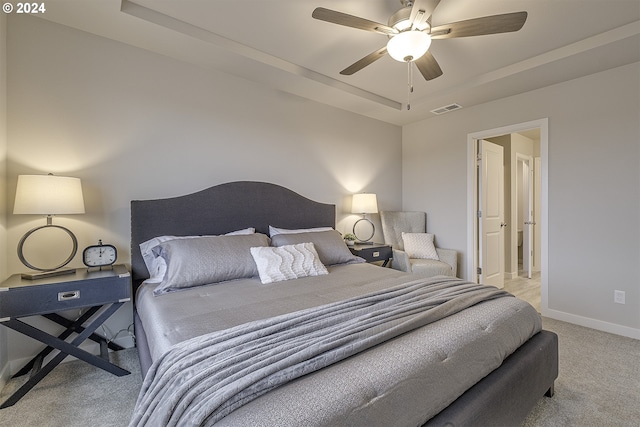 carpeted bedroom featuring ceiling fan and a tray ceiling