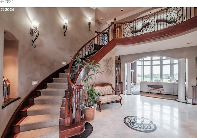 stairs with decorative columns and a high ceiling