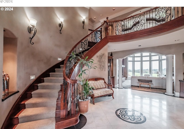 stairs featuring arched walkways, a high ceiling, tile patterned floors, and baseboards