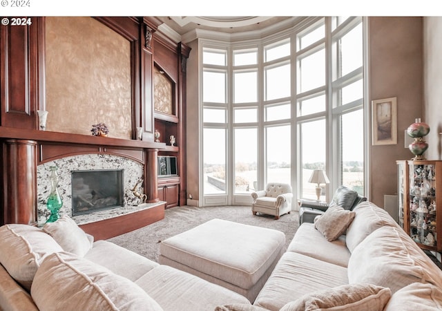 living room with light carpet, a high end fireplace, a towering ceiling, and crown molding