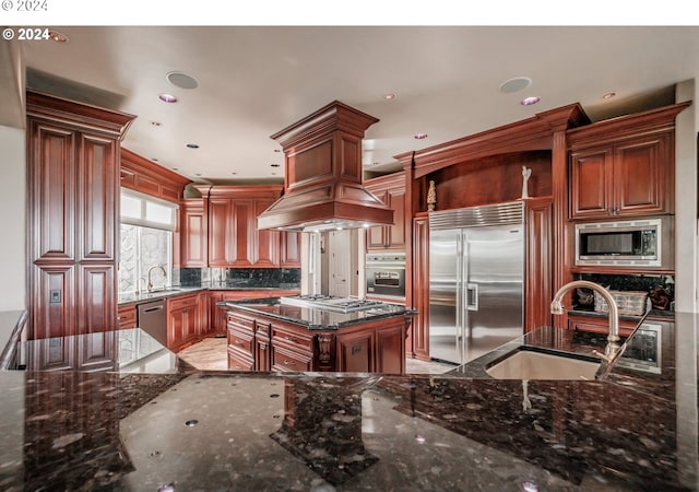 kitchen with built in appliances, a sink, open shelves, dark stone countertops, and recessed lighting
