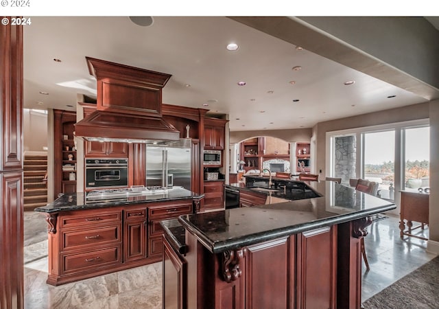 kitchen featuring a spacious island, black appliances, arched walkways, recessed lighting, and a sink