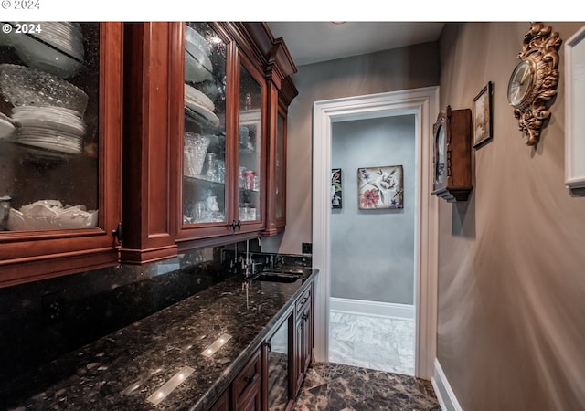 indoor wet bar with dark marble finish floors and baseboards