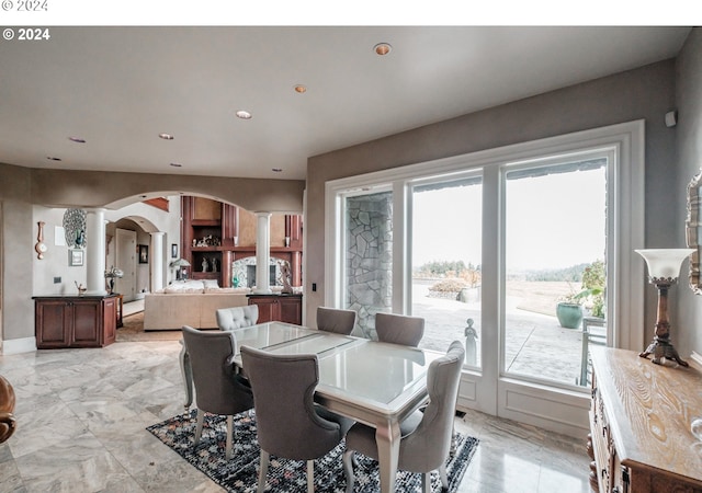 dining space featuring ornate columns, arched walkways, recessed lighting, and light marble finish floors
