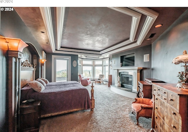 carpeted bedroom featuring a high end fireplace, a raised ceiling, and ornamental molding