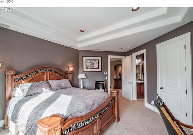 carpeted bedroom with connected bathroom and a raised ceiling