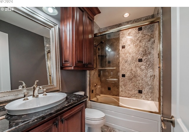 full bath featuring toilet, bath / shower combo with glass door, and vanity