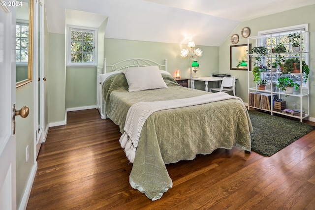 bedroom featuring dark wood-type flooring, lofted ceiling, and an inviting chandelier