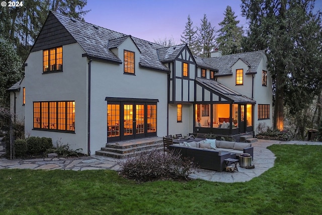 back house at dusk with an outdoor hangout area and a lawn