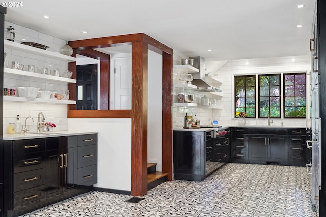 bar featuring backsplash, wall chimney exhaust hood, and sink