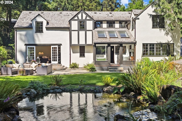 rear view of house with an outdoor hangout area, a water view, and a lawn