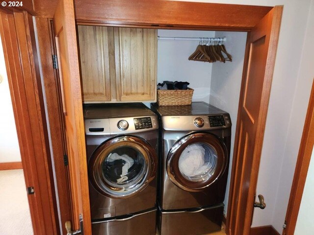 clothes washing area featuring washer and clothes dryer and cabinets