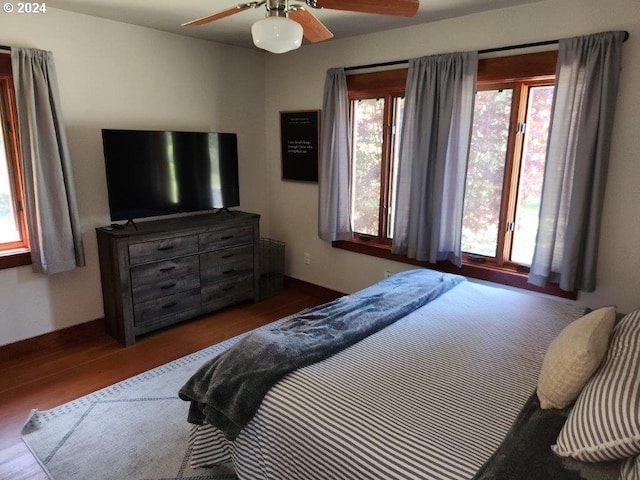 bedroom featuring ceiling fan, dark wood-type flooring, and multiple windows