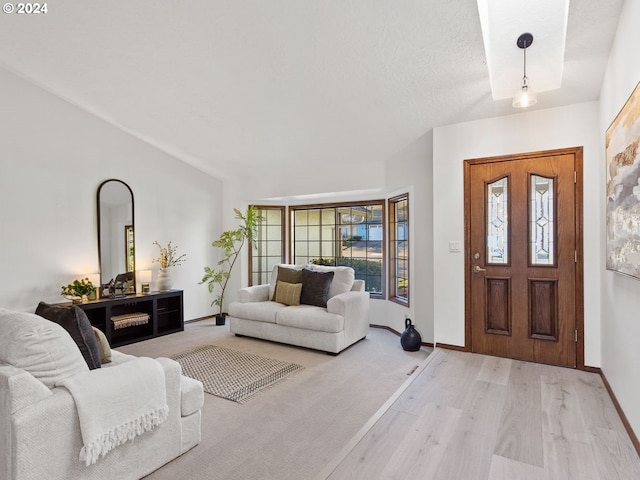 interior space with vaulted ceiling, a textured ceiling, and light hardwood / wood-style flooring