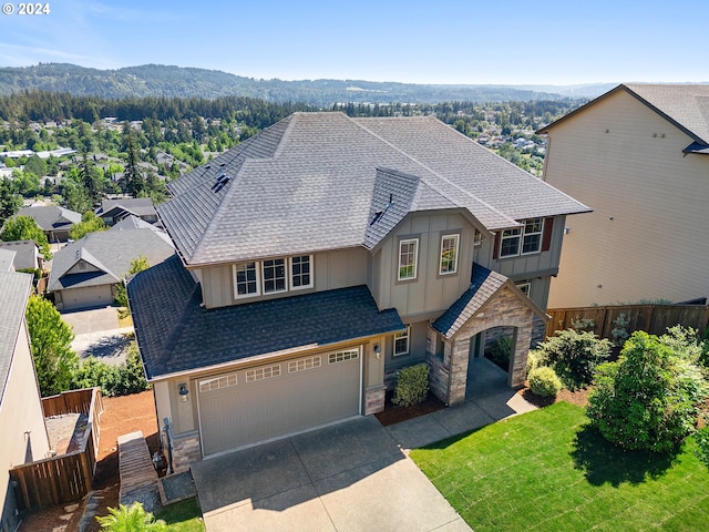 view of front facade featuring a garage, a mountain view, and a front yard