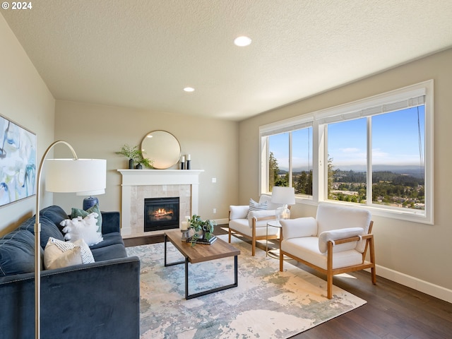 living room with a textured ceiling, a tile fireplace, and dark hardwood / wood-style flooring