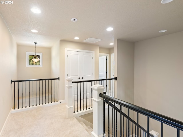 corridor featuring a textured ceiling and light colored carpet