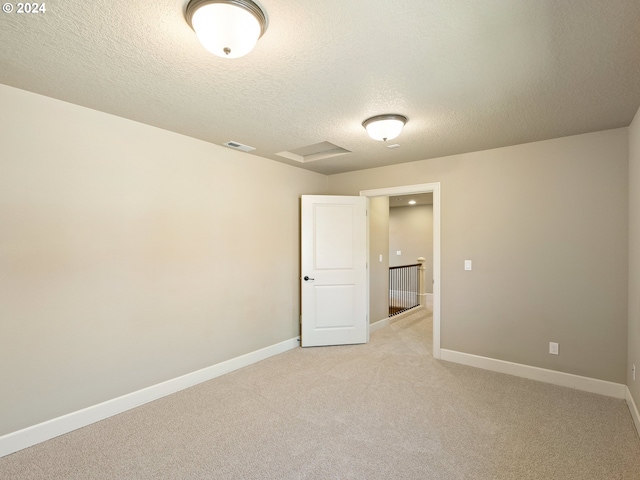 empty room with a textured ceiling and light colored carpet