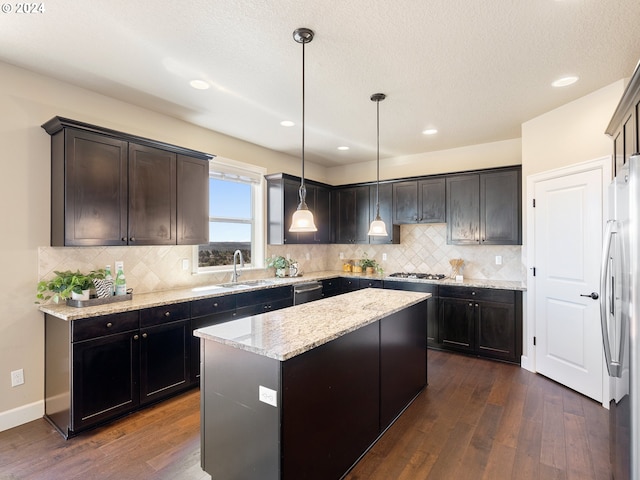 kitchen featuring pendant lighting, stainless steel appliances, a center island, and dark hardwood / wood-style floors