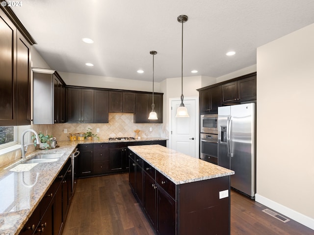 kitchen with hanging light fixtures, sink, stainless steel appliances, dark hardwood / wood-style floors, and a center island