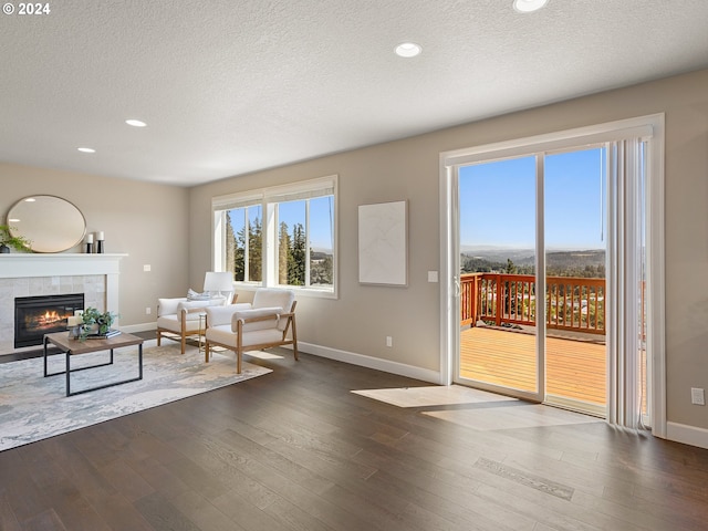 unfurnished living room featuring a tiled fireplace, a textured ceiling, and dark wood-type flooring