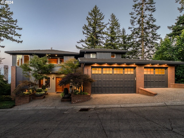 view of front of house with brick siding, a garage, and decorative driveway
